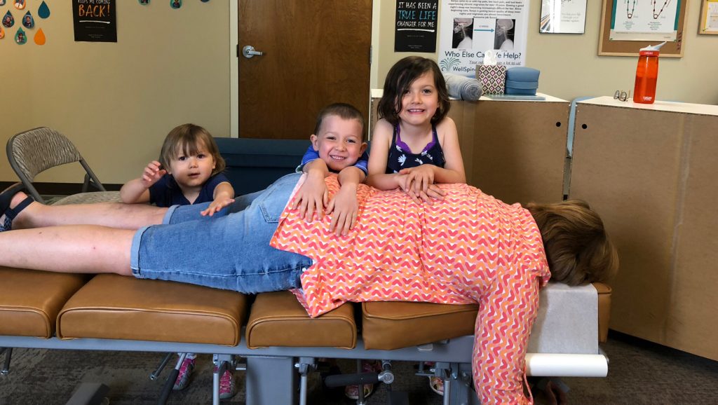 3 children laying on top of grandma